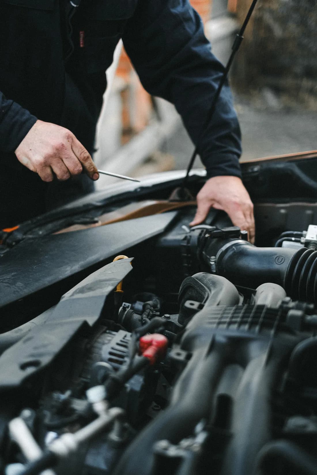 A mechanic carrying out work in a car’s engine compartment